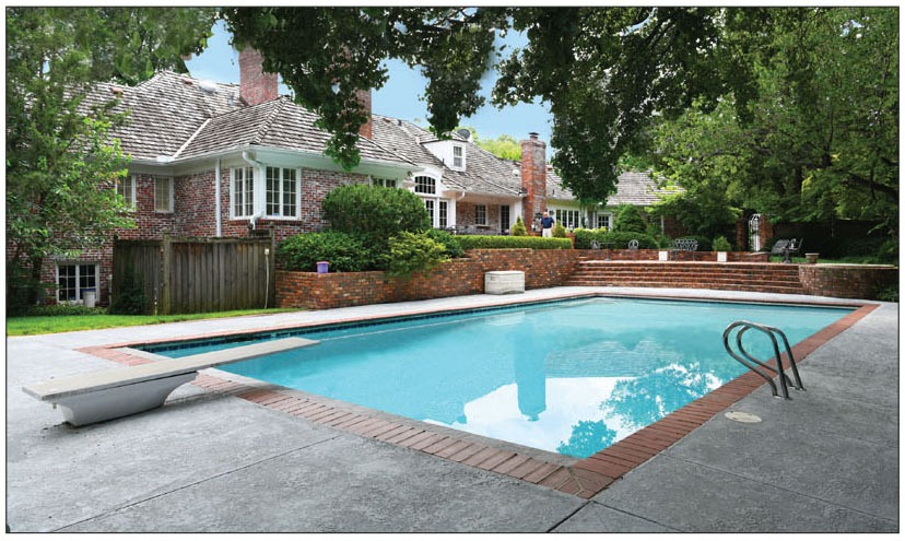 A backyard pool surrounded by a patio and a house, showcasing a serene outdoor living space.